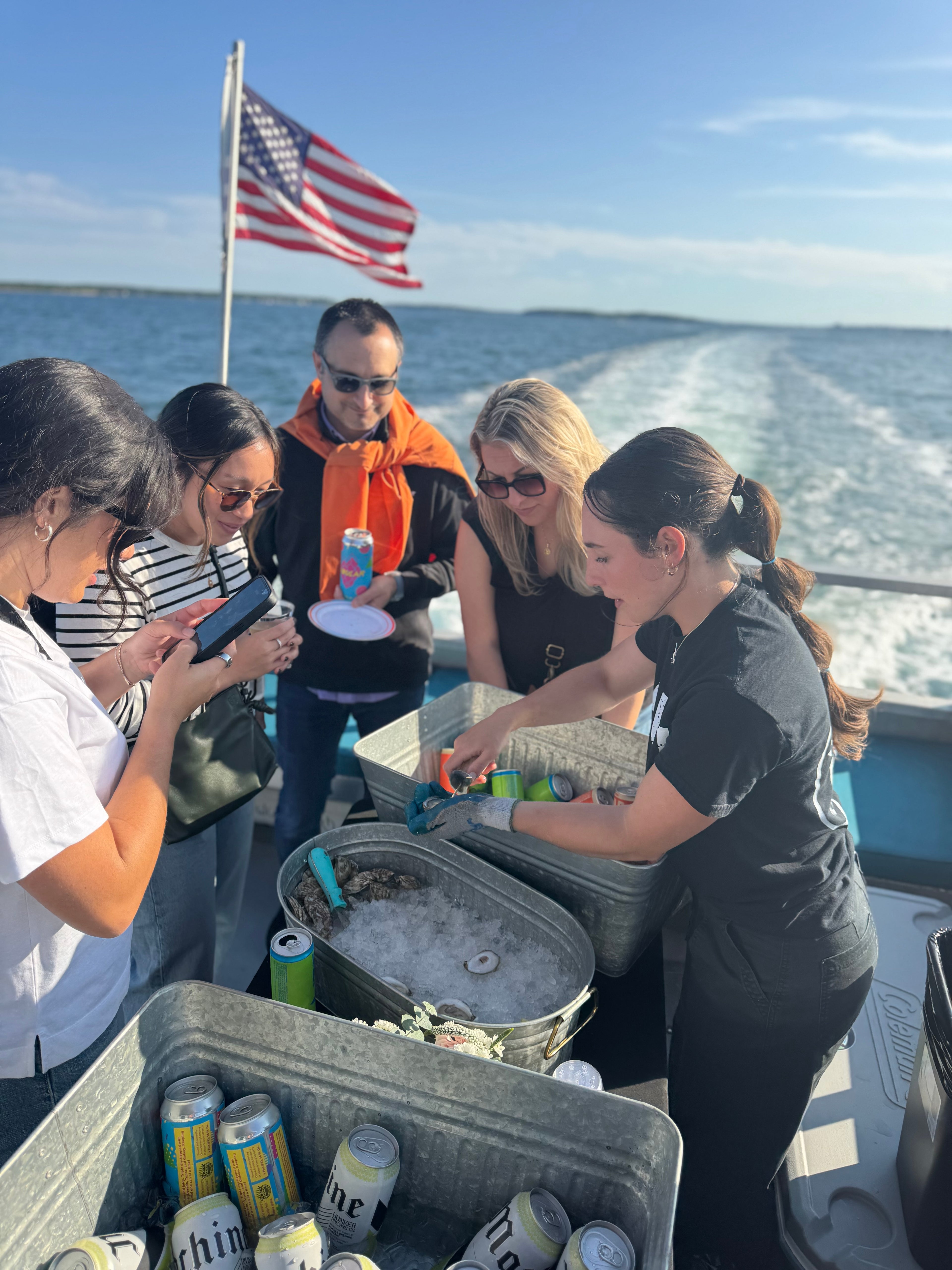 Group of people on a boat with coolers and drinks, American flag in the background